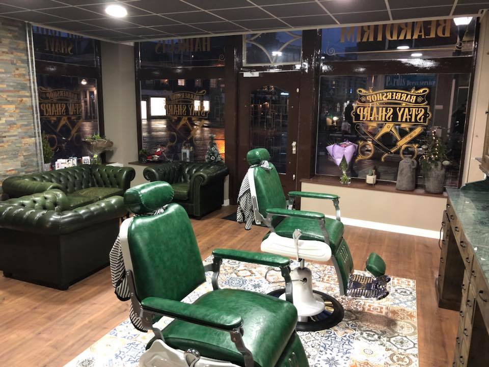 Het interieur: groene leren barbierstoelen, Chesterfield banken en een tegelkleed, 's avonds